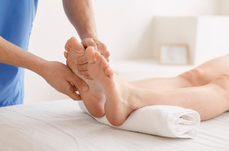 Close-up image of a therapist's hands kneading and applying pressure to the soles of a foot.